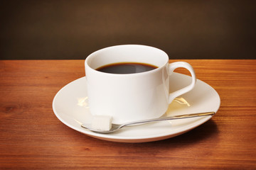 Coffee cup on wooden table on brown background