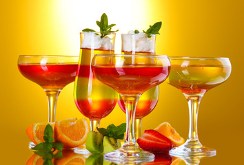 fruit jelly in glasses and fruits on yellow background