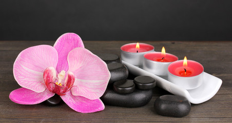 Spa stones with orchid and candles on table on grey background