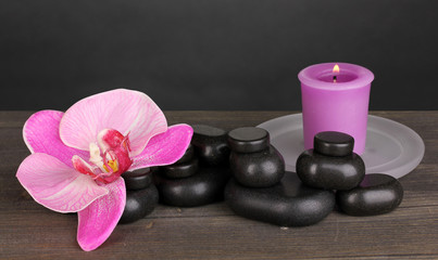 Spa stones with orchid and candles on table on grey background