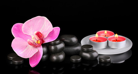 Fototapeta na wymiar Spa stones with orchid flower and candles isolated on black