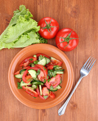 Fresh salad with tomatoes and cucumbers on wooden background
