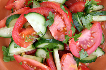 Fresh salad with tomatoes and cucumbers on wooden background