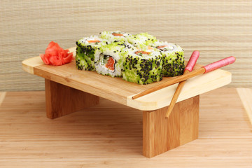 Tasty rolls served on wooden plate on wooden background
