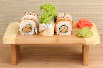 Tasty rolls served on wooden plate on wooden background