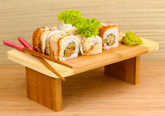 Tasty rolls served on wooden plate on wooden background