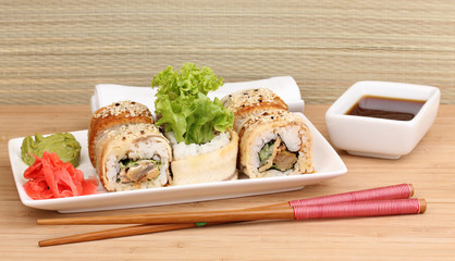 Tasty rolls served on plate with chopsticks on table