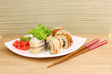 Tasty rolls served on plate with chopsticks on table