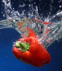Fotobehang Rode peper die in water valt. Blauwe achtergrond © Julián Rovagnati