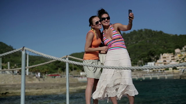 Happy female friends taking photo on pier, dolly shot