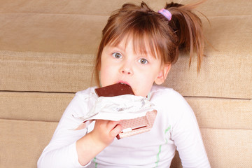 Beautiful little girl eating chocolate