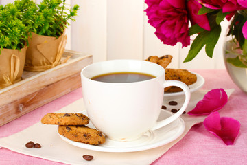cup of coffee, cookies and flowers on table in cafe