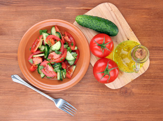 Fresh salad with tomatoes and cucumbers on wooden background