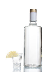 Bottle of vodka and wineglass with lemon isolated on white