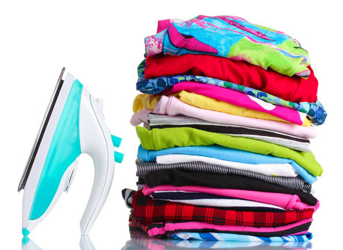 Pile of colorful clothes and electric iron isolated on white