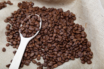 Coffee beans and wooden spoon on sacking.