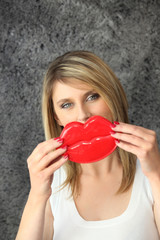 Blond woman holding novelty lips in  front of her face