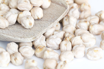 chickpeas on wooden spoon and white background