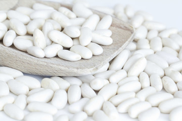 Fototapeta na wymiar White beans on wooden spoon and a white background
