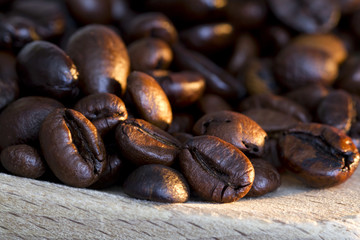Coffee beans on wooden spoon and a white background