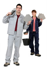 Tile fitters holding up their building supplies and tools