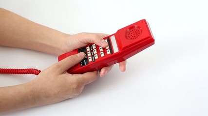 Woman is pressing the buttons of old red telephone
