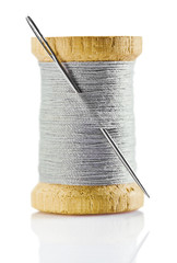 spool with gray thread and nidle