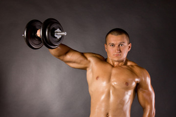 Muscled male bodybuilder dumbbell swing