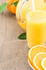orange juice in glass and slices on wood