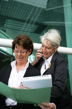 Two senior businesswomen with folders