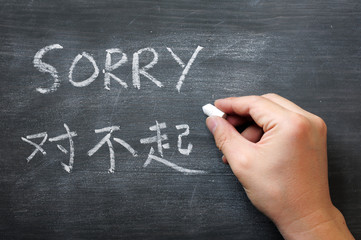 Sorry - word written on a smudged blackboard