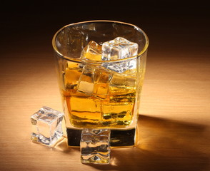 glass of scotch whiskey and ice on wooden table