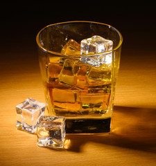 glass of scotch whiskey and ice on wooden table