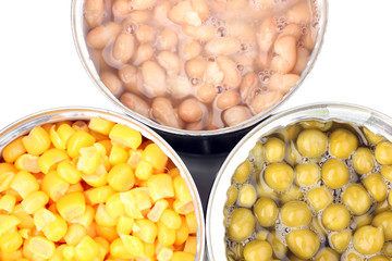 Open tin cans of corn, beans and peas close-up isolated on