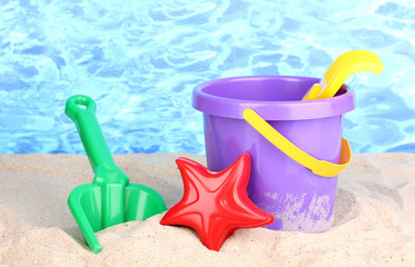 Fototapeta na wymiar Children's beach toys on sand on water background