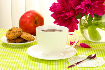 cup hot chocolate, apple, cookies and flowers on table in cafe