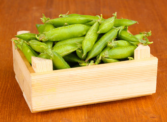 Green peas in crate on wooden background