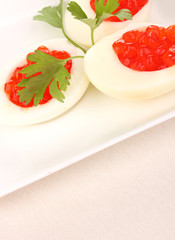 Red caviar in eggs on white plate on cloth