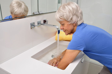 Seniorin macht Wechselbäder im Waschbecken