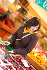 Beautiful young woman buying cherries at market