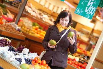 Beautiful young woman buying mangoes at market
