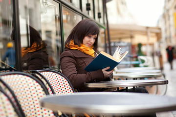 Beautiful young woman reading a book in cafe