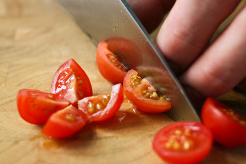 Cutting cherry tomatoes on a wooden chopping board