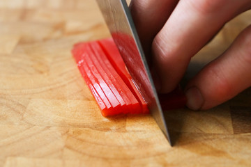 Cutting red peppers on a wooden chopping board