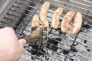 Turning sausages on the barbecue with tongs