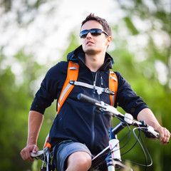 Naklejka premium Handsome young man biking in the countryside