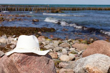 Strohhut liegt auf Felsen an der Küste