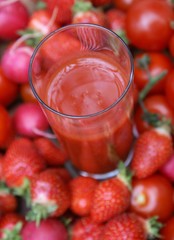 Ein Glas frisch gepresster Saft zwischen Früchten