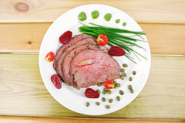 roasted meat served on white dish over wood