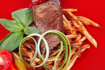 meat steak on potatoes over red dish